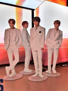Standee người in hình nhân vật với trang phục vest trắng sang trọng, tạo cảm giác nổi bật và chuyên nghiệp, phù hợp trưng bày tại sự kiện hoặc không gian quảng bá.